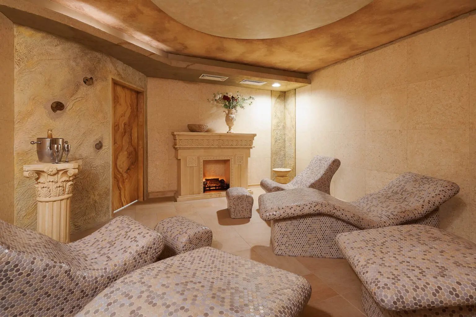 Luxusní moderní interiér wellness s elegantními lehátky a dekorativním krbem.