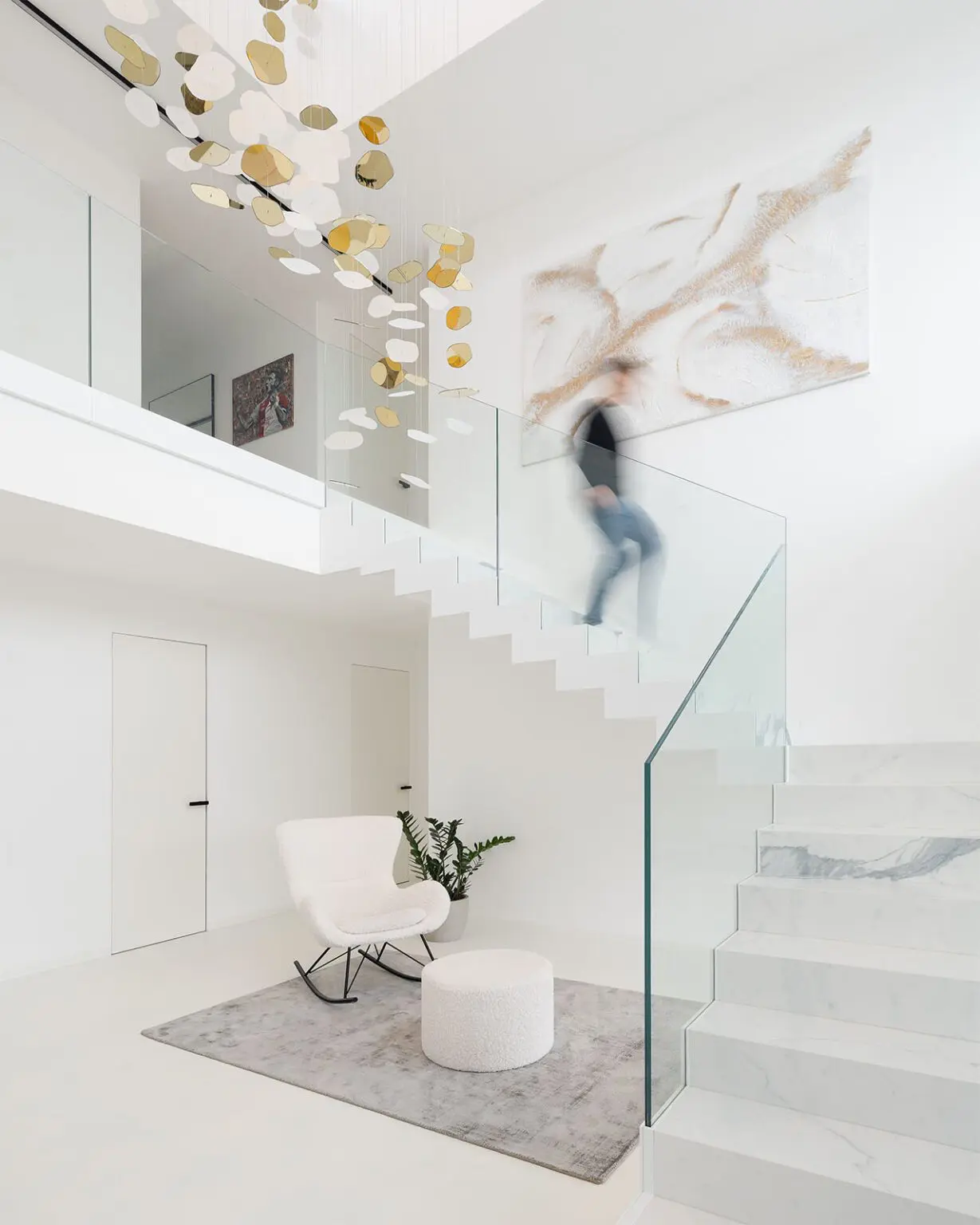 Moderní minimalistický interiér se schodištěm a skleněným zábradlím. Designové osvětlení.