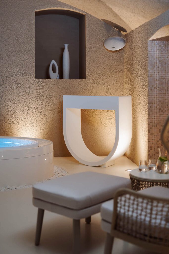 Designový moderní interiér spa s béžovými stěnami, vířivkou a dekorativním stolem ve tvaru U.